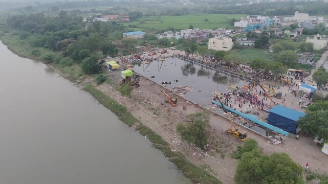 Riverside kund with festival crowd aerial, Drone view of river ghat and city crowd, Aerial riverbank with pond and people gathering, Top view of riverside kund near town stock video.