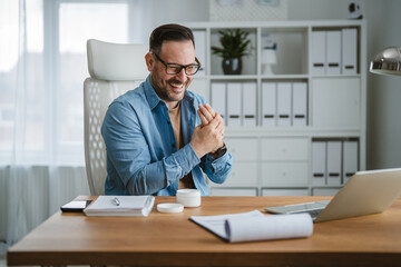 Naklejka premium Man applying hand cream for hand care and skincare at office