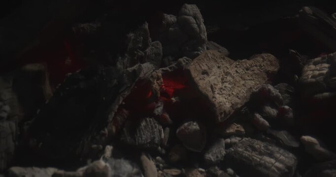 Close up of smoldering charcoal with glowing embers and ash texture in low light, ideal for fire, heat, grilling, fuel, and dramatic background concepts.