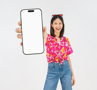Portrait of young Asian woman in summer wearing floral shirt holding smartphone mockup of blank screen and smiling on white background.