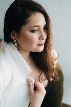 A beautiful woman in white looks thoughtfully into the distance. Brunette in a white jacket. A thoughtful beautiful lady. 