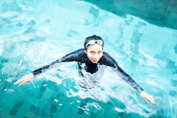 Young Asian Woman in Black Swimsuit and Goggles Swimming in Clear Blue Outdoor Pool