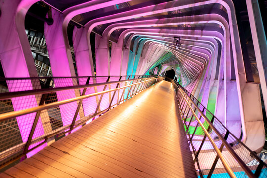 Wide Dynamic View of Phinisi Sudirman Pedestrian Bridge Interior with Neon LED Lighting at Night, Jakarta
