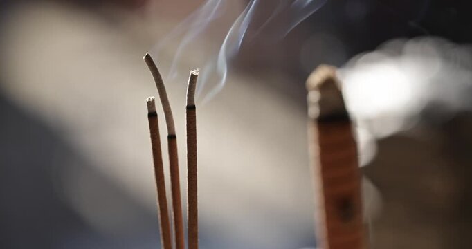Close-ups and shallow depth-of-field shots capture the moment when incense is burning, and smoke swirls in the temple, showcasing a solemn and tranquil cultural image.