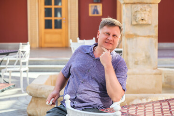 Portrait a handsome adult man at a table in a summer cafe.