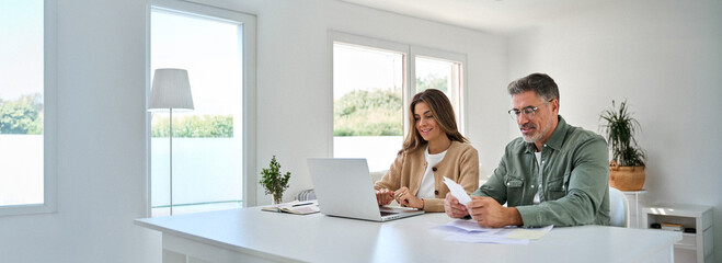 Older man and woman paying bills online planning financial budget savings calculating payments sit...