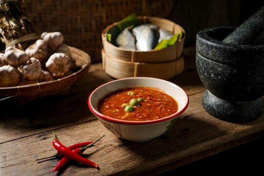 Authentic Thai Shrimp Paste Chili Sauce (Nam Prik Kapi) served with steamed mackerel, garlic, and red chilies in a traditional rustic kitchen setting.