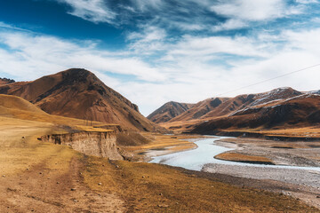 Naklejka premium Rugged mountain with turquoise river through rocky valley during autumn on wilderness