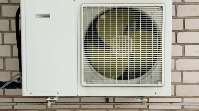 Close-up of an industrial air conditioner fan, radiator grille, rotating blades, gears. Routine inspection and repair.