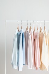 Fototapeta premium Pastel clothes hang neatly on a white rack in a minimalist space with bright lighting and open areas for a fresh look