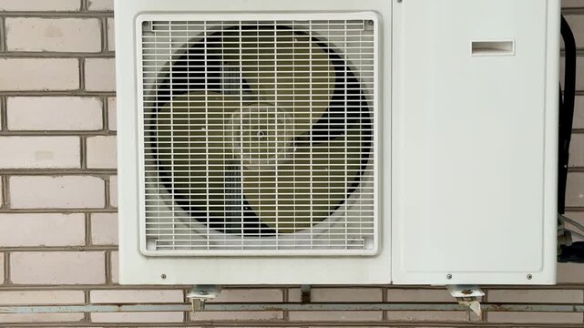 Close-up of an industrial air conditioner fan, radiator grille, rotating blades, gears. Routine inspection and repair.