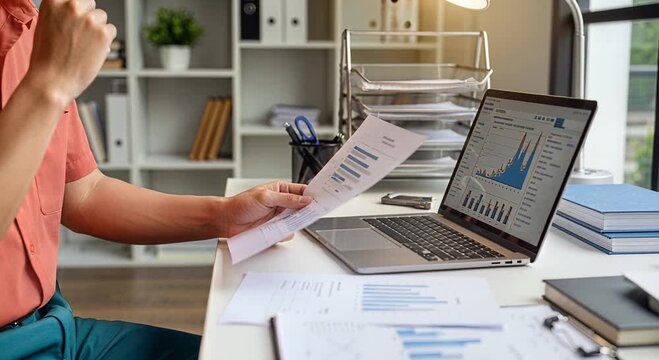 Person analyzing financial data at desk with laptop and documents
