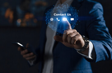 Businessman in suit uses smartphone touching glowing contact us icon with phone email and chat symbols