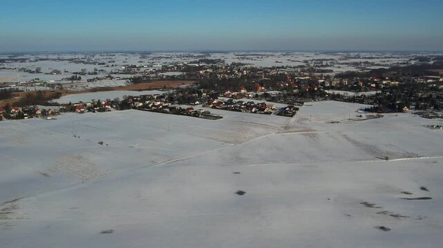 Winter aerial of rural town and snowy fields under blue sky, contryside landscape 4k.