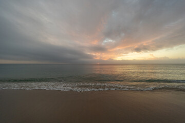 Obraz premium Calm Ocean Sunrise with Gentle Waves and Soft Pastel Sky at Dawn