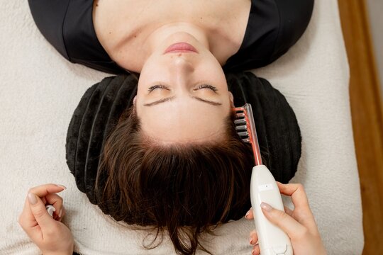 The doctor is doing a hair care procedure for a girl using darsonval