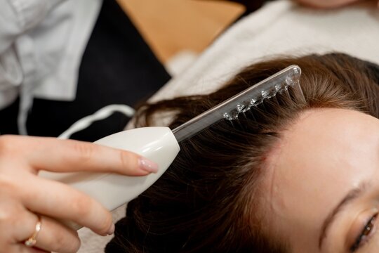 The doctor is doing a hair care procedure for a girl using darsonval