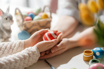 Fototapeta premium Close Up of Family Hands Holding Painted Easter Egg in Bright Spring Setting