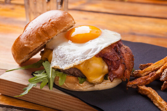 Hamburger with fried egg and bacon, served with fries.