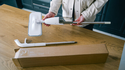 Assembling a new spray mop with a refillable water tank and cleaning pad on a wooden table © shine.graphics