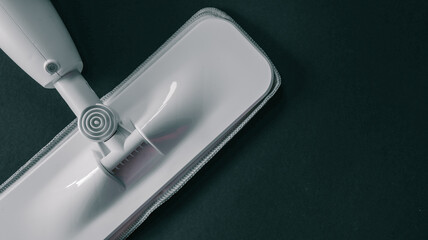 Modern spray mop with microfiber pad for efficient floor cleaning on a dark background © shine.graphics