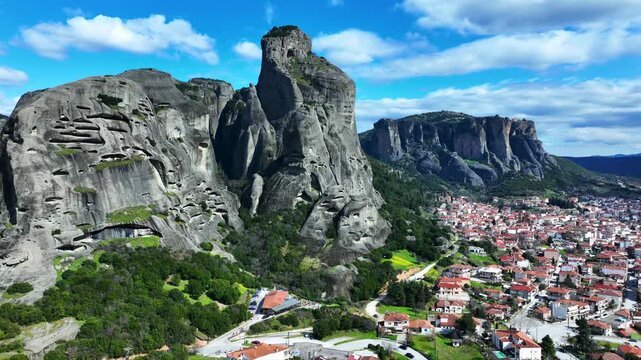 Aerial drone cinematic video of breathtaking view of famous rock pillars of Meteora featuring Orthodox monasteries as seen from village of Kalabaka, Thessaly, Greece