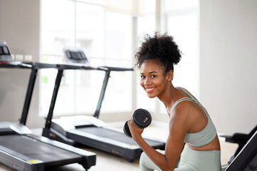 Sporty fitness African American woman working out with dumbbells strength and strength endurance at the gym.
