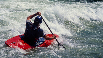 Whitewater kayaker navigating powerful rapids, extreme river paddling action. Crashing waves and splashing water. Control and adrenaline in extreme sport concept.