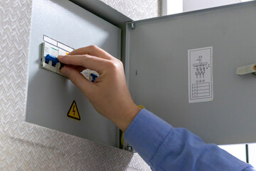 A man checks an indoor circuit breaker box. Electric