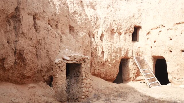 Panorama: Traditional troglodyte houses carved into rock in Matmata, Tunisia. Ancient underground dwellings in arid desert landscape, historic Berber architecture and cultural heritage site
