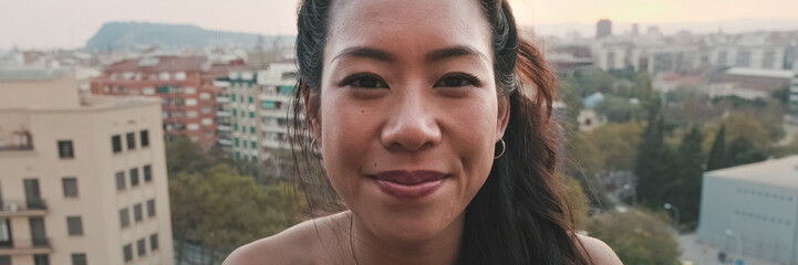 Fototapeta premium Close-up of lovely young woman with cute smile posing for the camera while standing on the balcony. Panoramic. Panoramic