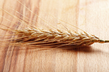 Naklejka premium Wheat stalk placed on wooden surface in natural light
