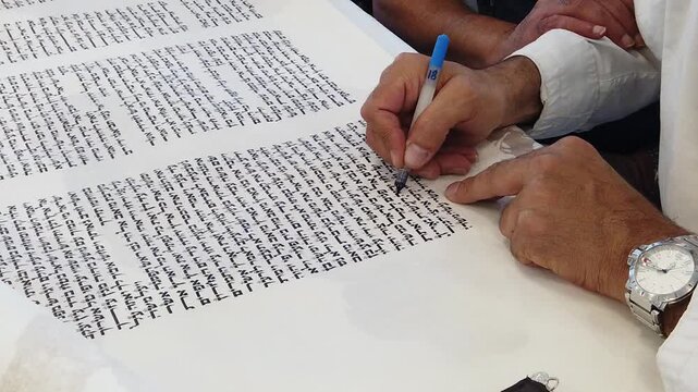 Close-up of a Jewish Sofer scribe writing Hebrew letters in a Holy Torah Scroll, Jewish tradition and religious ceremony
