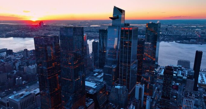 Light of setting sun goes through the glass skyscrapers. Vast cityscape of New York from drone at sunset.