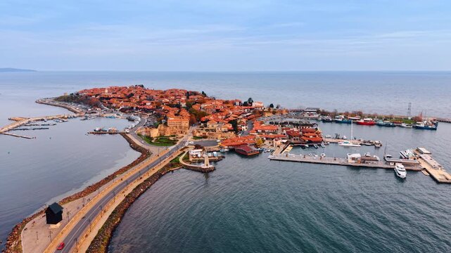 Aerial view of ancient coastal peninsula town. Drone shot of a historical seaside town located on a narrow peninsula surrounded by water.