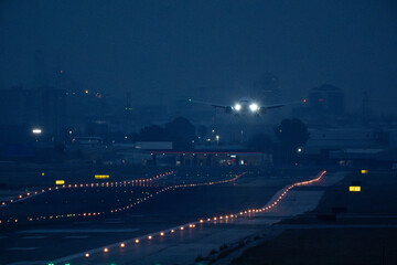 Fototapeta premium Front view of a passenger aircraft with bright lights moving along the airport landing strip at night