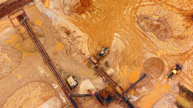 Industrial sand processing plant with conveyors and heavy machinery. Aerial view of conveyor belts and loaders at mining site