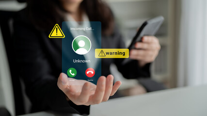 A professional woman looks at her smartphone displaying an incoming unknown call with a warning...