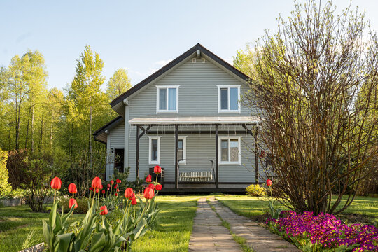Modern country house with spring garden and red tulips in sunny yard