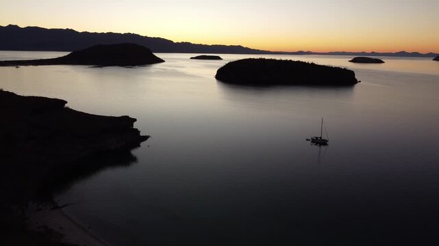 Fly around islands in ocean at sunset 