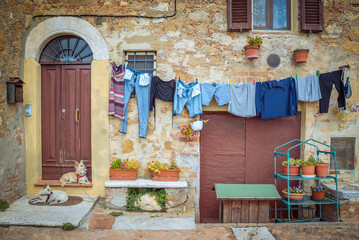 Pienza, Toscana, Italy: Clothes drying on a line outside a rustic building with dogs