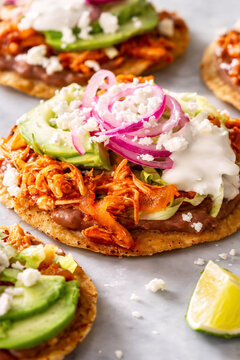 Tostadas mexicanas de tinga de pollo con frijoles, crema, queso fresco y aguacate