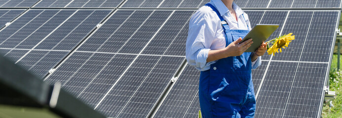 Female farmer with digital tablet on a modern farm using solar panels. Agricultural silos in the background. © scharfsinn86