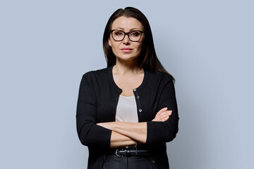 Portrait of serious confident mature woman on grey background