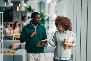 Coworkers discussing business while walking in office