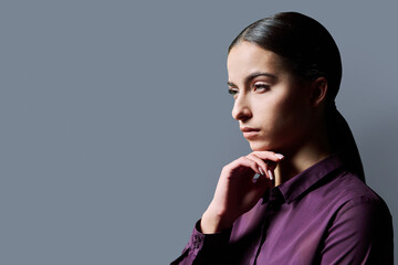 Profile portrait of young serious woman on gray background © Valerii Honcharuk