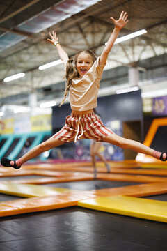 14.01.26 Vinnitsa, Ukraine: A young girl leaps high with arms wide open on a colorful trampoline full of joy and energy in an indoor play
