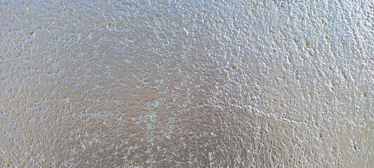 Vista de primer plano de una superficie metálica con textura rugosa y reflejos brillantes de color plata