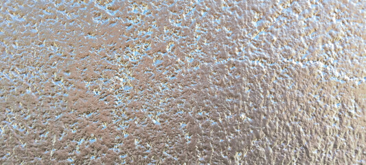 Vista de primer plano de una superficie metálica con textura rugosa y reflejos brillantes de color...