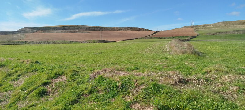 Paisaje rural de praderas verdes y colinas bajo un cielo azul despejado en Burgos, Espa&ntilde;a